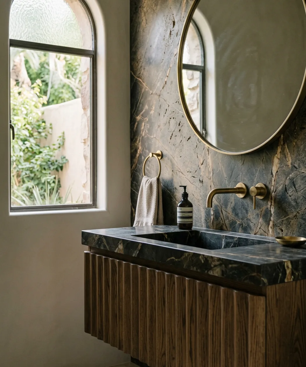 Natural stone powder room design for Arcadia Phoenix homes | PHX Interior Design Natural stone powder room design for Arcadia Phoenix homes: powder room with a dark gold-veined natural stone slab, a wall-mounted faucet and a floating vanity with wavy fluted wood slats